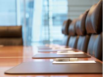 boardroom table with leather chairs, notepads and pens